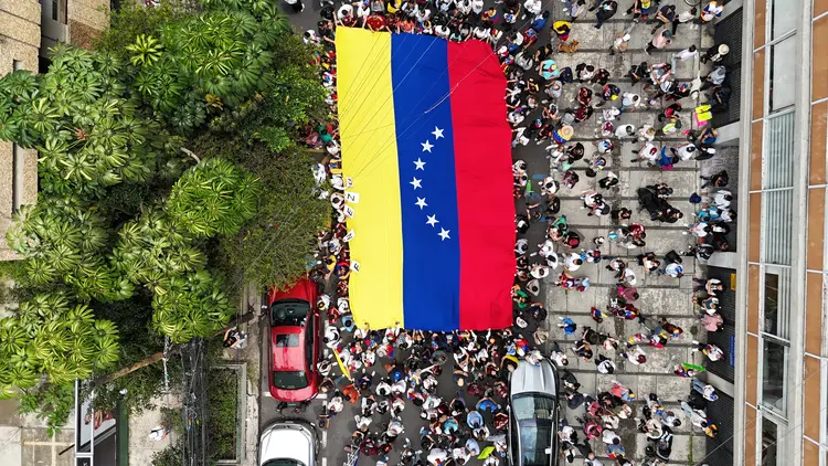 Vista aérea de uma bandeira venezuelana carregada por venezuelanos que vivem no México do lado de fora da embaixada da Venezuela na Cidade do México em 28 de julho de 2024, durante o dia da eleição em seu país. Os venezuelanos votam no domingo entre a continuidade do presidente Nicolás Maduro ou a mudança no rival Edmundo Gonzalez Urrutia em meio à alta tensão após a ameaça do titular de um "banho de sangue" se ele perder (ALFREDO ESTRELLA/AFP)