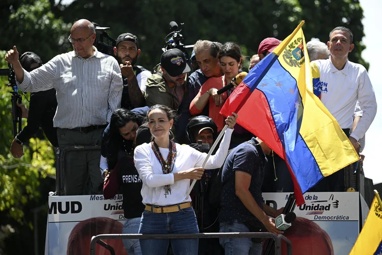 A líder da oposição venezuelana Maria Corina Machado agita uma bandeira nacional durante uma manifestação para protestar contra os resultados das eleições presidenciais, em Caracas, em 3 de agosto de 2024. Depois de passar vários dias escondida, a líder da oposição venezuelana Maria Corina Machado compareceu a um comício com milhares de manifestantes, acompanhada por vários líderes da oposição, mas não por seu candidato presidencial Edmundo Gonzalez Urrutia (Federico PARRA/AFP)