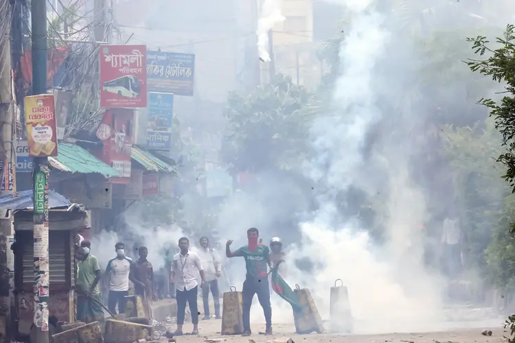 Manifestantes fogem de bombas de gás nas ruas de Bogura ((Photo by AFP))