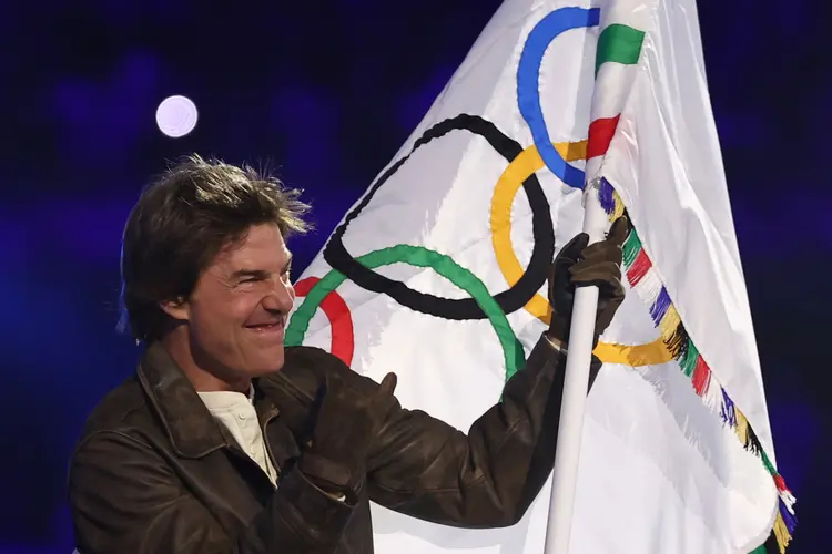 O ator americano Tom Cruise acena a bandeira olímpica durante a cerimônia de encerramento dos Jogos Olímpicos de Paris 2024 no Stade de France, em Saint-Denis, nos arredores de Paris, em 11 de agosto de 2024 (Franck FIFE/AFP)