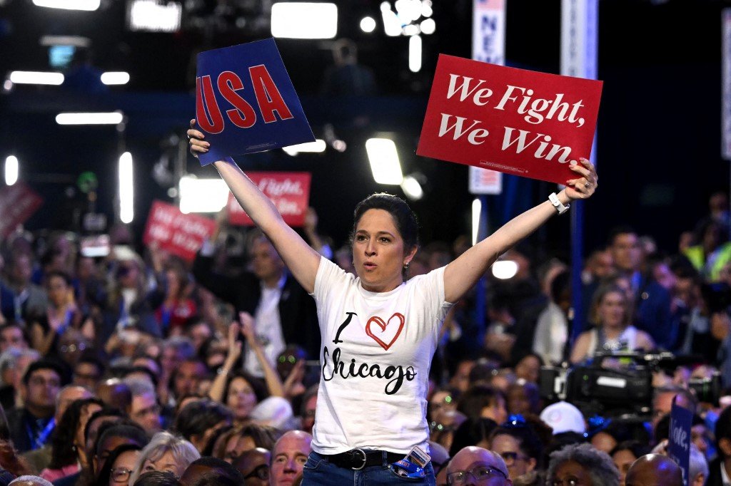 Uma participante segura placas no primeiro dia da Convenção Nacional Democrata (DNC) no United Center, em Chicago, Illinois, em 19 de agosto de 2024.