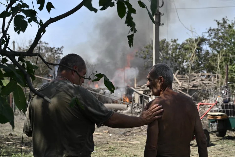 Civis observam casa destruída na região de Donetsk ((Photo by Genya SAVILOV / AFP))