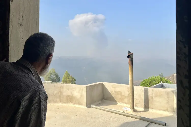 Homem observa fumaça vinda de ataque israelense na vila libanesa de Qsair ((Photo by AFP))