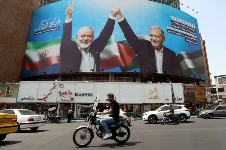 Líder do Hamas morto no Irã, Ismail Haniyeh, aparece ao lado do presidente iraniano, Masoud Pezeshkian, em placa de publicidade em Teerã (AFP)