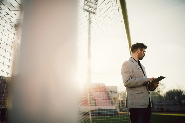 One man, standing on soccer field, using digital tablet. (South_agency/Getty Images)