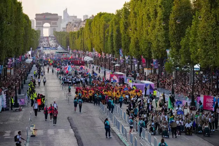 Atletas desfilam pela Champs-Elysees, em final de tarde sem chuva  (Dimitar DILKOFF/AFP)