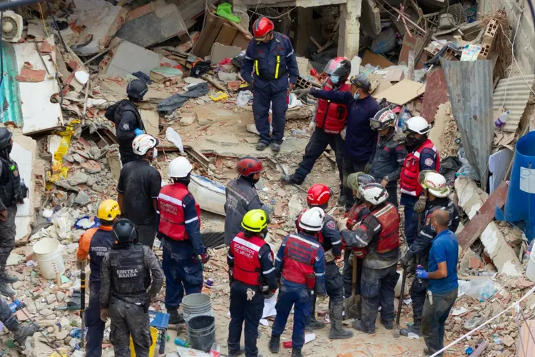 Bombeiros observam os escombros de uma casa destruída após acúmulo de gás que causou seu desabamento em 12 de agosto de 2024, no bairro Unión, em Petare, Caracas (AFP)