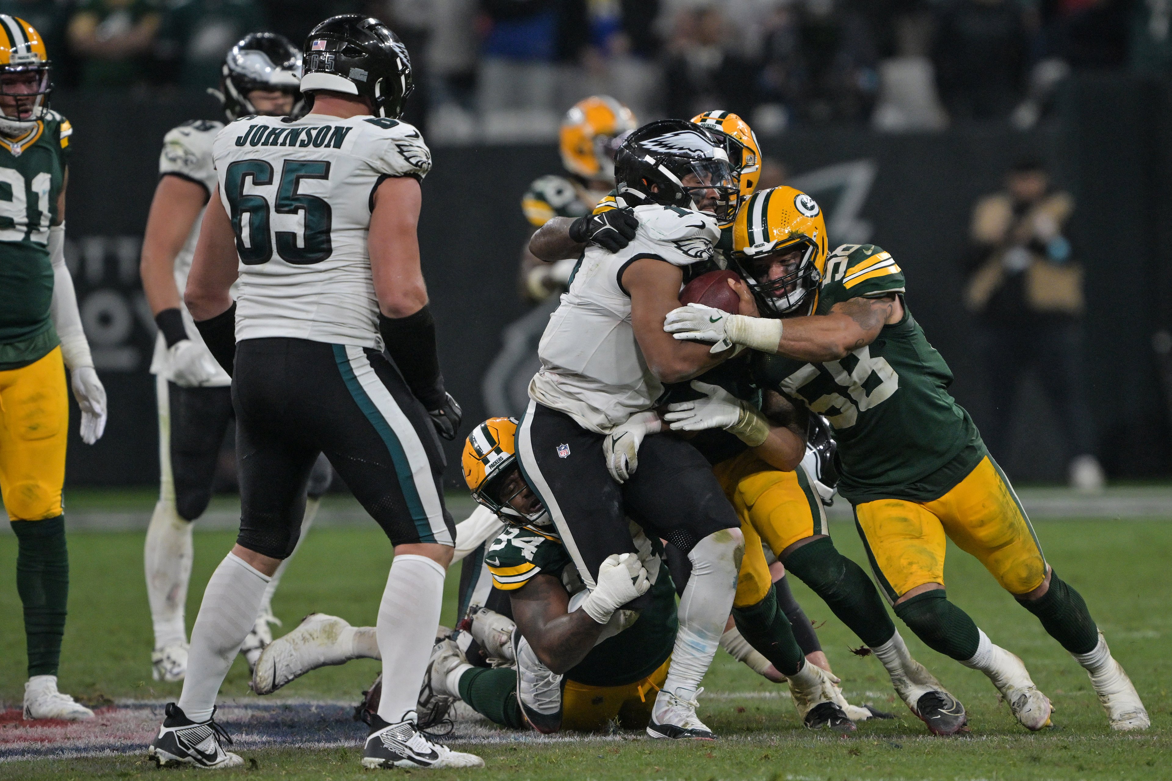 Eagles Jalen Hurts (C) é derrubado pelos Packers Karl Brooks (abaixo) e Isaiah McDuffie (D) durante a partida de futebol americano da NFL entre Philadelphia Eagles e Green Bay Packers