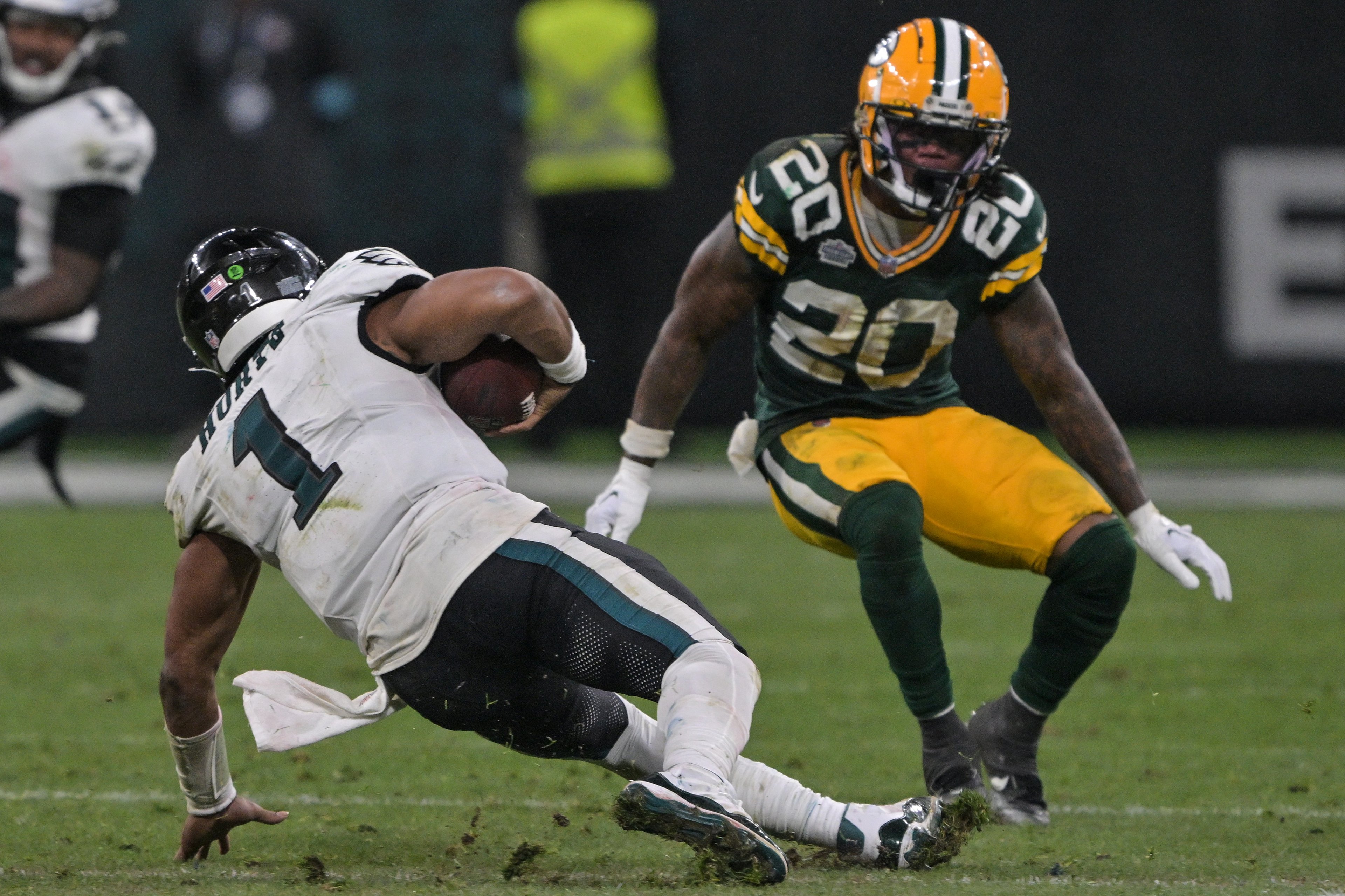 Eagles Jalen Hurts (E) cai com a bola sob pressão do Packers Javon Bullard durante a partida de futebol americano da NFL entre Philadelphia Eagles e Green Bay Packers