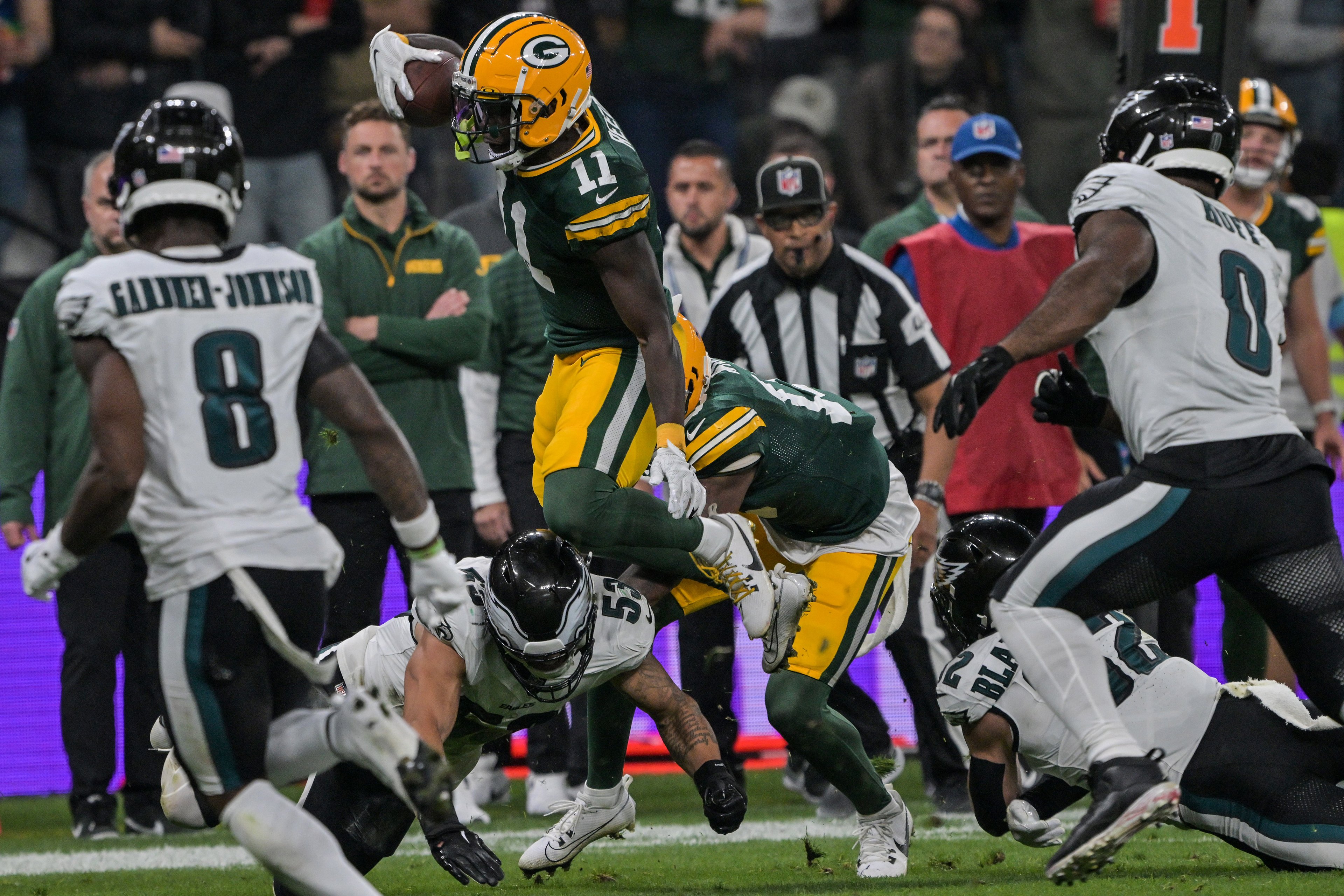 Jayden Reed (C) do Green Bay Packers é derrubado por Zack Baun (abaixo) do Philadelphia Eagles durante a partida de futebol americano da NFL Philadelphia Eagles x Green Bay Packers, na Neo Química Arena, em São Paulo, Brasil