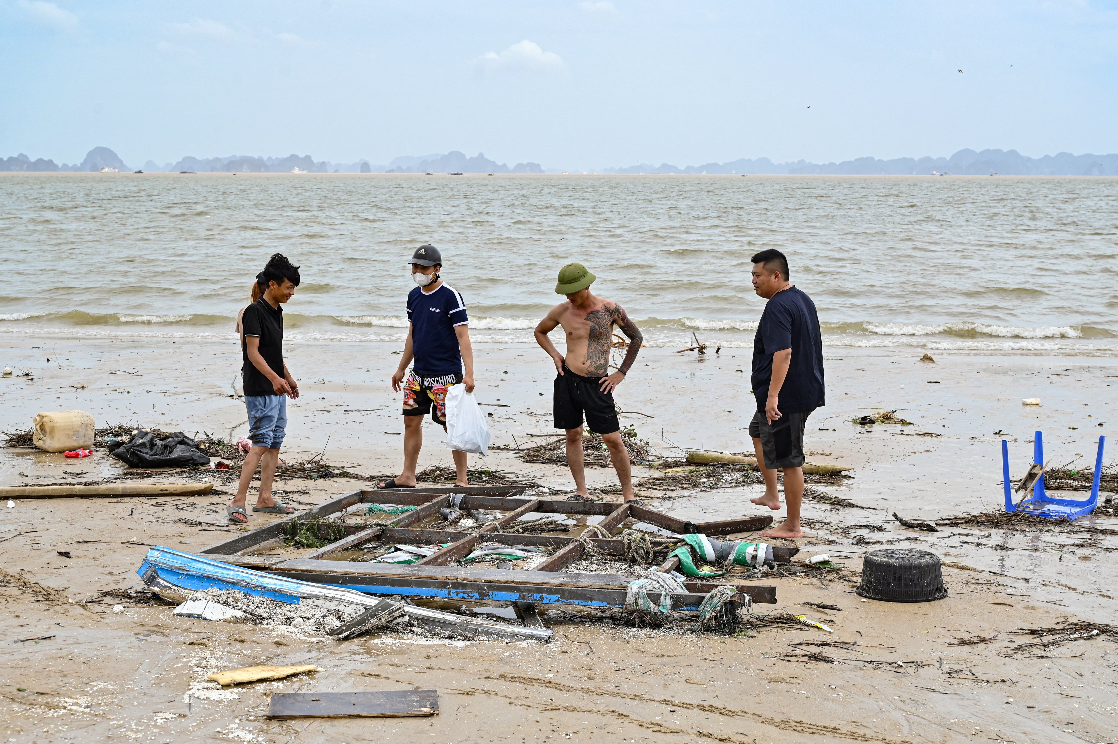 Pessoas inspecionam destroços na praia de Bai Chay após o Super Tufão Yagi atingir Ha Long, na província de Quang Ninh, em 8 de setembro de 2024. Super Tufão Yagi arranca milhares de árvores, arrasta navios e barcos para o mar e arranca telhados de casas no norte do Vietname, depois de deixar um rastro de destruição no sul da China e nas Filipinas