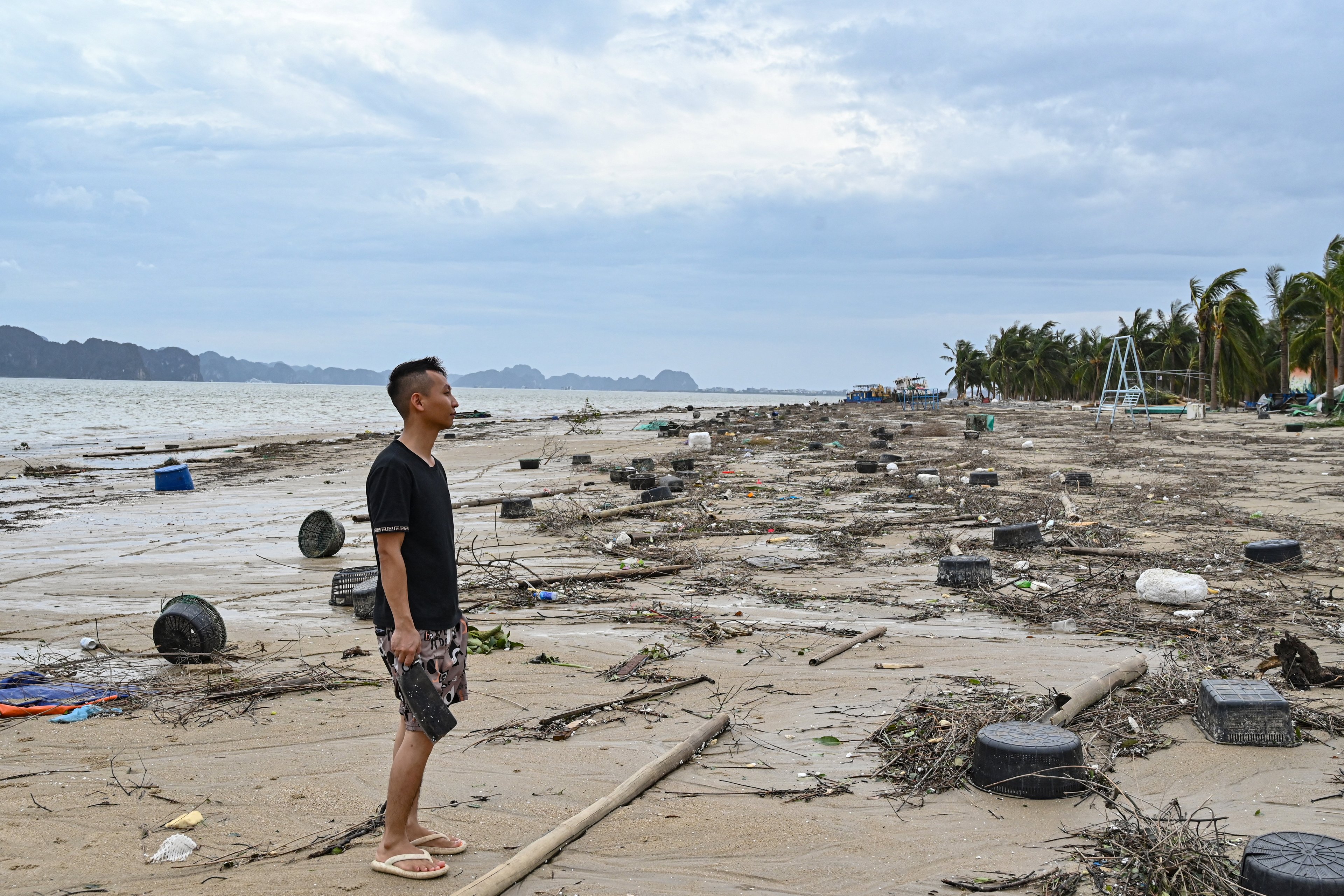 Um homem está em meio aos destroços na praia de Bai Chay após o Super Tufão Yagi atingir Ha Long, na província de Quang Ninh, em 8 de setembro de 2024. O Super Tufão Yagi arranca milhares de árvores, varre navios e barcos para o mar e arranca telhados de casas no norte do Vietnã, após deixar um rastro de destruição no sul da China e nas Filipinas