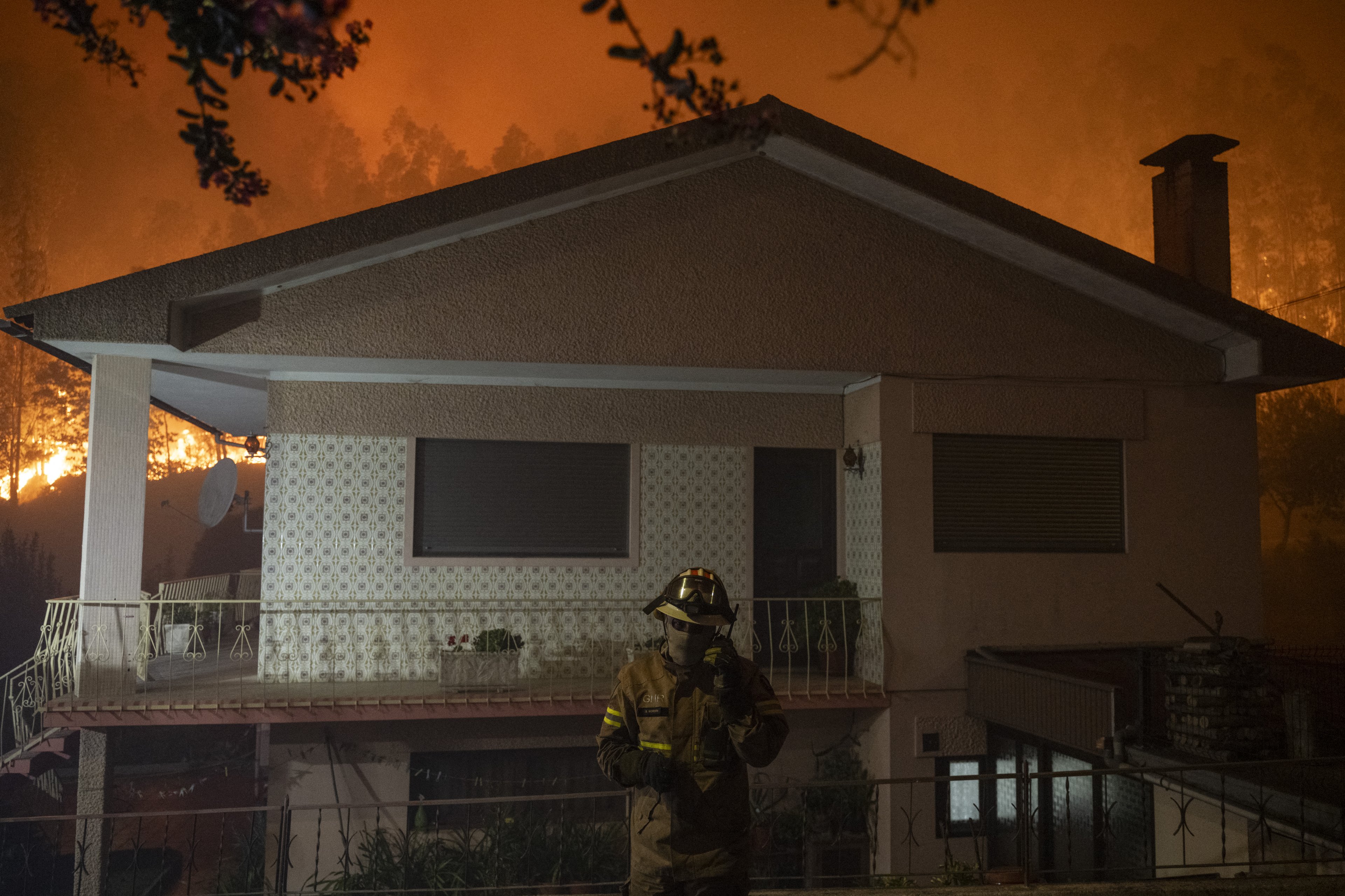 Um bombeiro fala no seu wlakie-talkie enquanto um incêndio florestal se aproxima das casas em Ribeira de Fraguas, Albergaria-a-Velha, em Aveiro, a 16 de setembro de 2024. Portugal recebeu hoje promessas de apoio dos seus parceiros europeus no combate aos incêndios florestais do norte que têm matou duas pessoas e feriu uma dúzia de bombeiros, disseram as autoridades