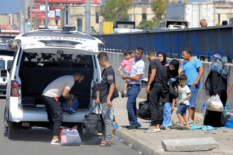 Pessoas deslocadas pelo conflito do sul do Líbano desembarcam de um veículo na beira de uma estrada em Beirute em 24 de setembro de 2024 (AFP)