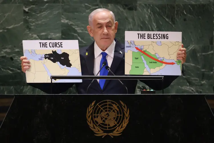 O primeiro-ministro israelense Benjamin Netanyahu fala durante a 79ª Sessão da Assembleia Geral das Nações Unidas na sede da ONU, em Nova York. Na imagem, o mapa da esquerda mostra os países inimigos de Israel como "maldição" e os aliados como "benção". Muitos delegados imediatamente se retiraram
 (Charly Triballeu/AFP)