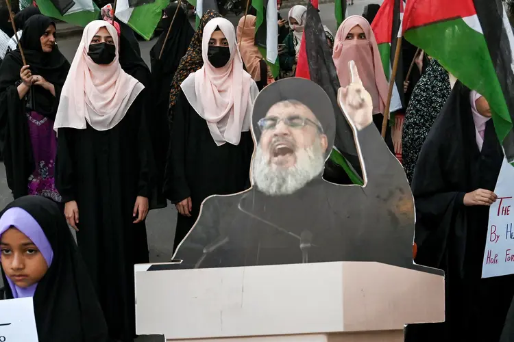 Shiite Muslims carrying Palestinian national flags stand beside a portrait of slain Lebanese Hezbollah chief Hassan Nasrallah, during an anti-Israel protest in Lahore on September 28, 2024. Hezbollah chief Hassan Nasrallah has been killed, the Lebanese movement said on September 28, dealing a seismic blow to the Iran-backed group that has been engaged in a year of cross-border hostilities with Israel. (Photo by Arif ALI / AFP) (Arif ALI/AFP)