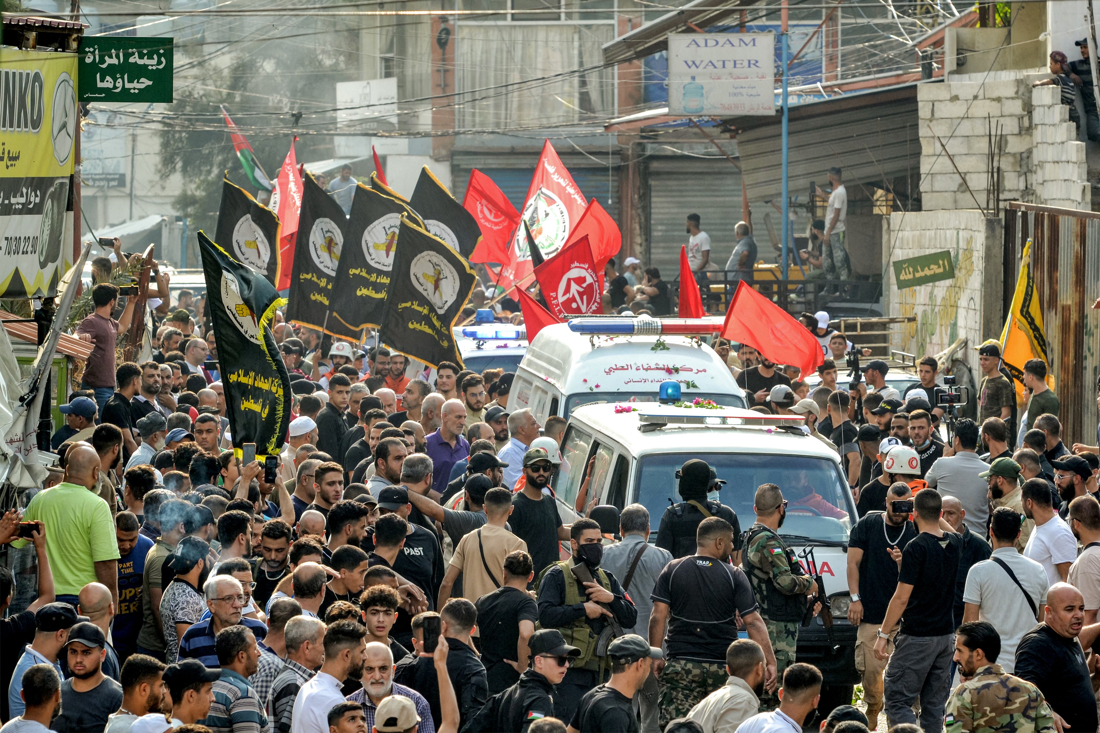 Mourners gather by ambulances transporting the bodies of two commanders and one member of the Popular Front For the Liberation of Palestine (PFLP) who were killed by an overnight Israeli air strike in Beirut, during the funeral at the Beddawi camp for Palestinian refugees near Lebanon's northern city of Tripoli on September 30, 2024. (Photo by Fathi AL-MASRI / AFP)