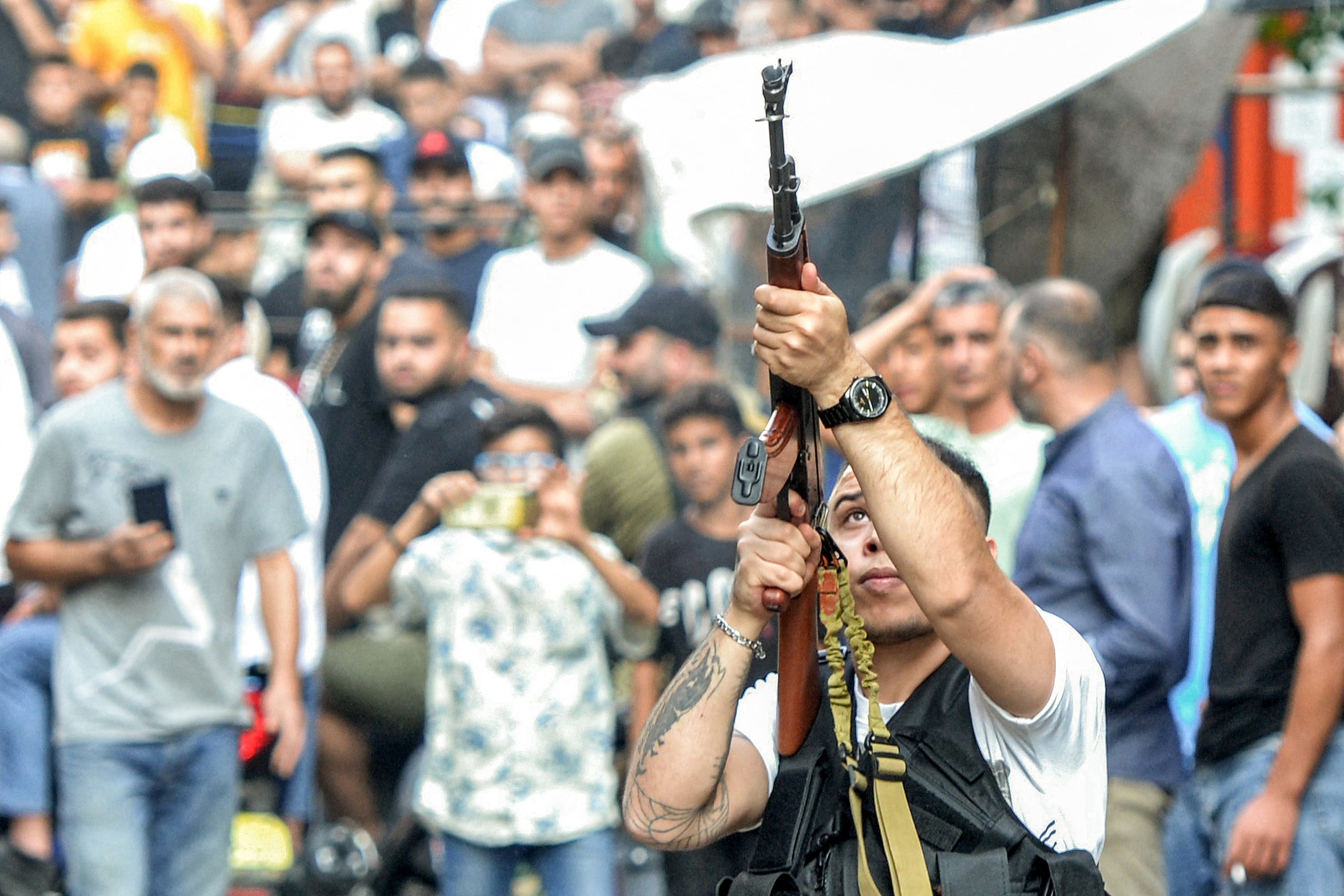 A fighter fires live rounds into the air from an assault rifle during the funeral of two commanders and one member of the Popular Front For the Liberation of Palestine (PFLP) group who were killed by an overnight Israeli air strike in Beirut, at the Beddawi camp for Palestinian refugees near Lebanon's northern city of Tripoli on September 30, 2024. (Photo by Fathi AL-MASRI / AFP)