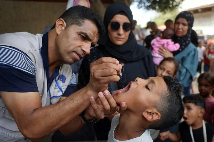 Trabalhador de saúde administra vacina da poliomielite em um menino em Zawayda, centro da Faixa de Gaza, em 1º de setembro de 2024 (AFP)