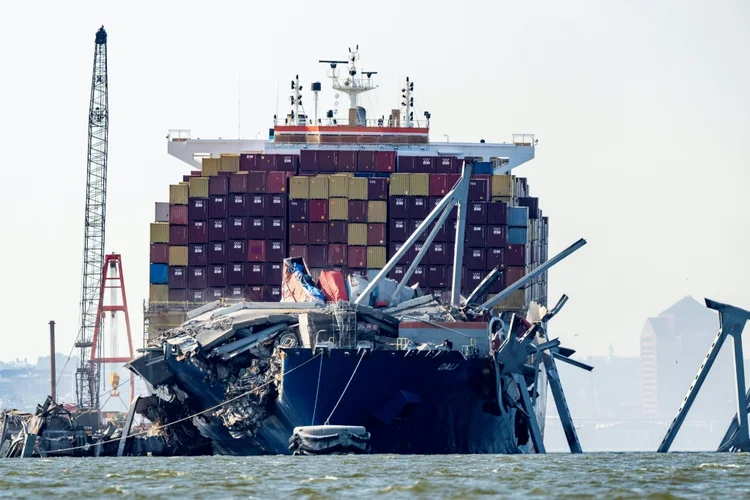 Uma seção da ponte Francis Scott Key repousa na água ao lado do navio porta-contêineres Dali, em Baltimore, em 13 de maio de 2024 (Agence France-Presse/AFP)