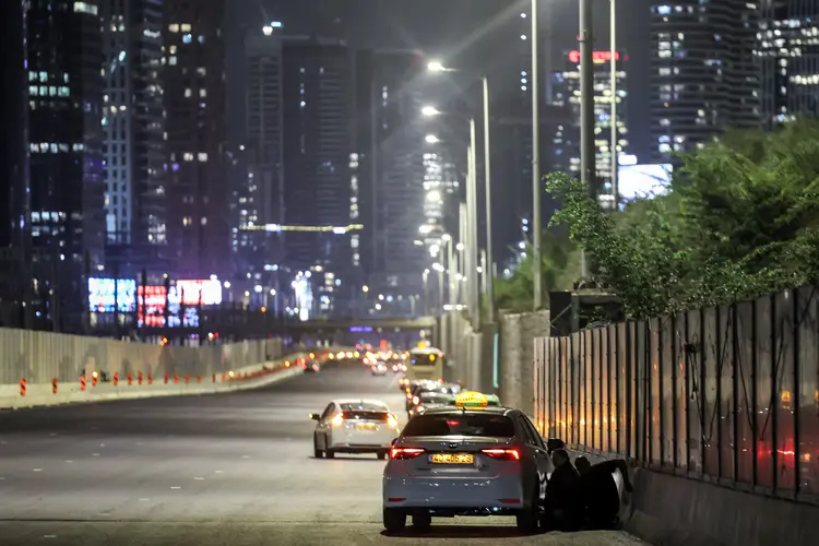 Pessoas se abrigam atrás de veículos sob uma ponte ao lado de uma rodovia em Tel Aviv, em 1º de outubro de 2024. Sirenes de ataque aéreo soaram no centro de Israel em 1º de outubro, informou o exército, um dia após o início das operações terrestres no sul do Líbano, visando posições do Hezbollah. (JACK GUEZ / AFP/AFP)