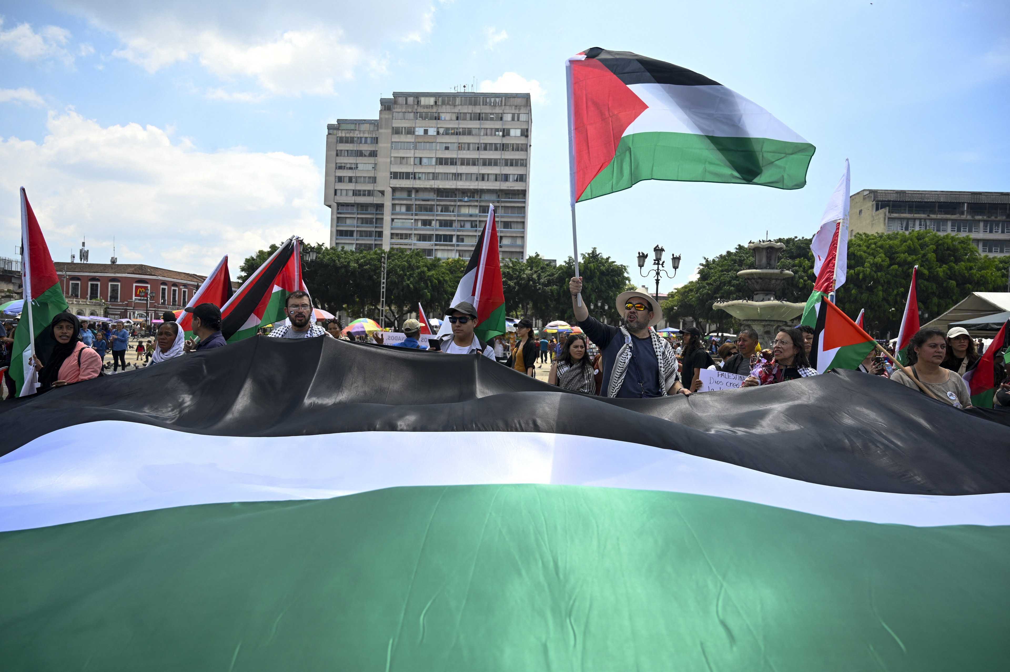 Manifestantes exibem uma bandeira palestina gigante durante uma marcha exigindo paz nos territórios palestinos e no Líbano, no âmbito do primeiro aniversário do conflito Israel-Hamas na Cidade da Guatemala em 6 de outubro de 2024