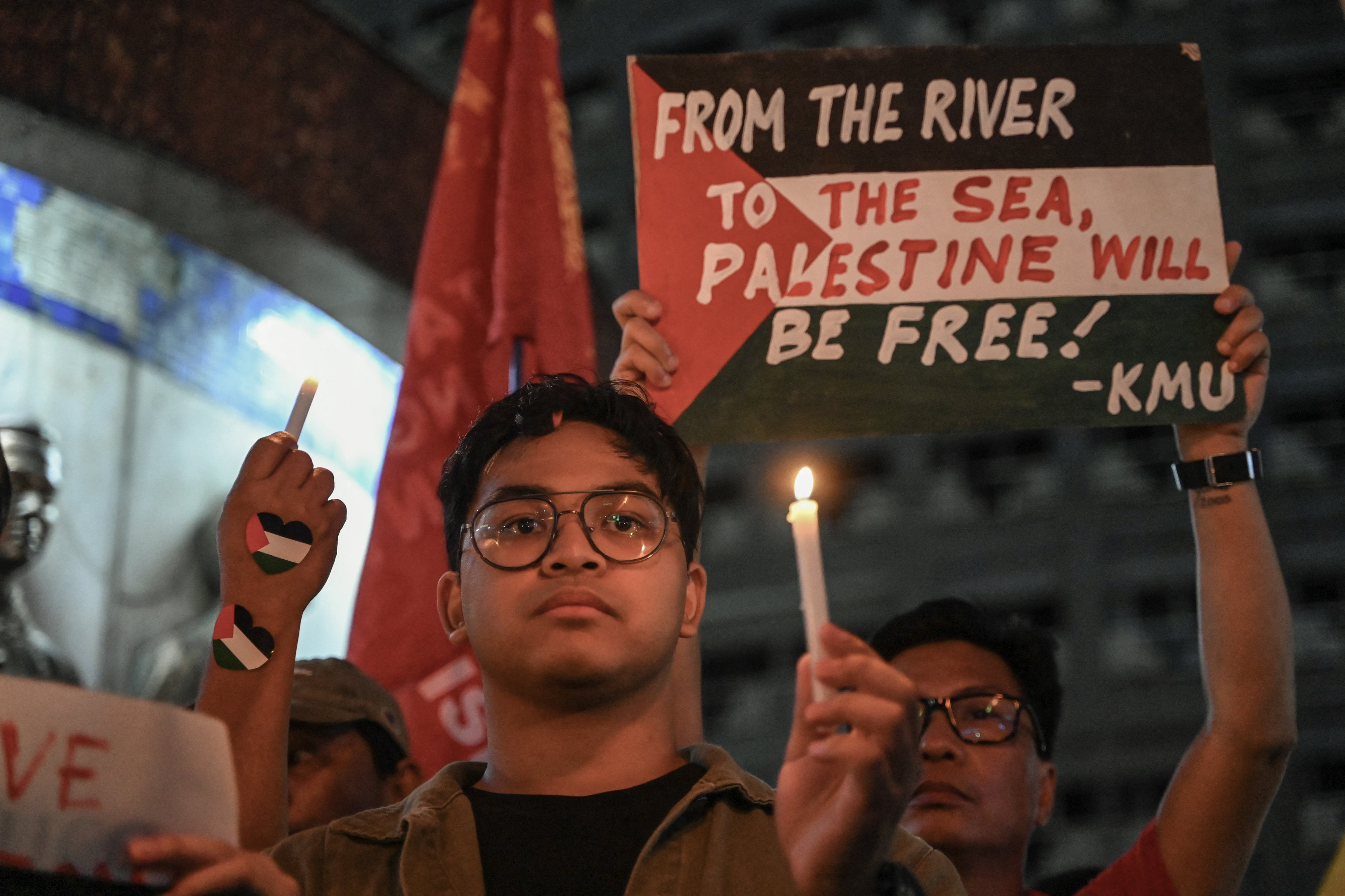 Manifestantes levantam cartazes e velas durante um comício pró-palestino realizado para marcar o primeiro aniversário do conflito Israel-Hamas, em Quezon City, Metro Manila, em 7 de outubro de 2024