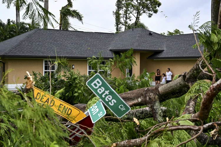 Pessoas do lado de fora de casa em Fort Myers, um dos lugares mais atingidas pelo furacão ((Photo by CHANDAN KHANNA / AFP))