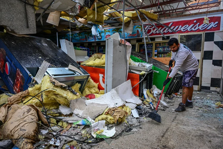 Homem começa limpeza em posto de combustível destruído em Lakewood (Giorgio Viera/AFP)