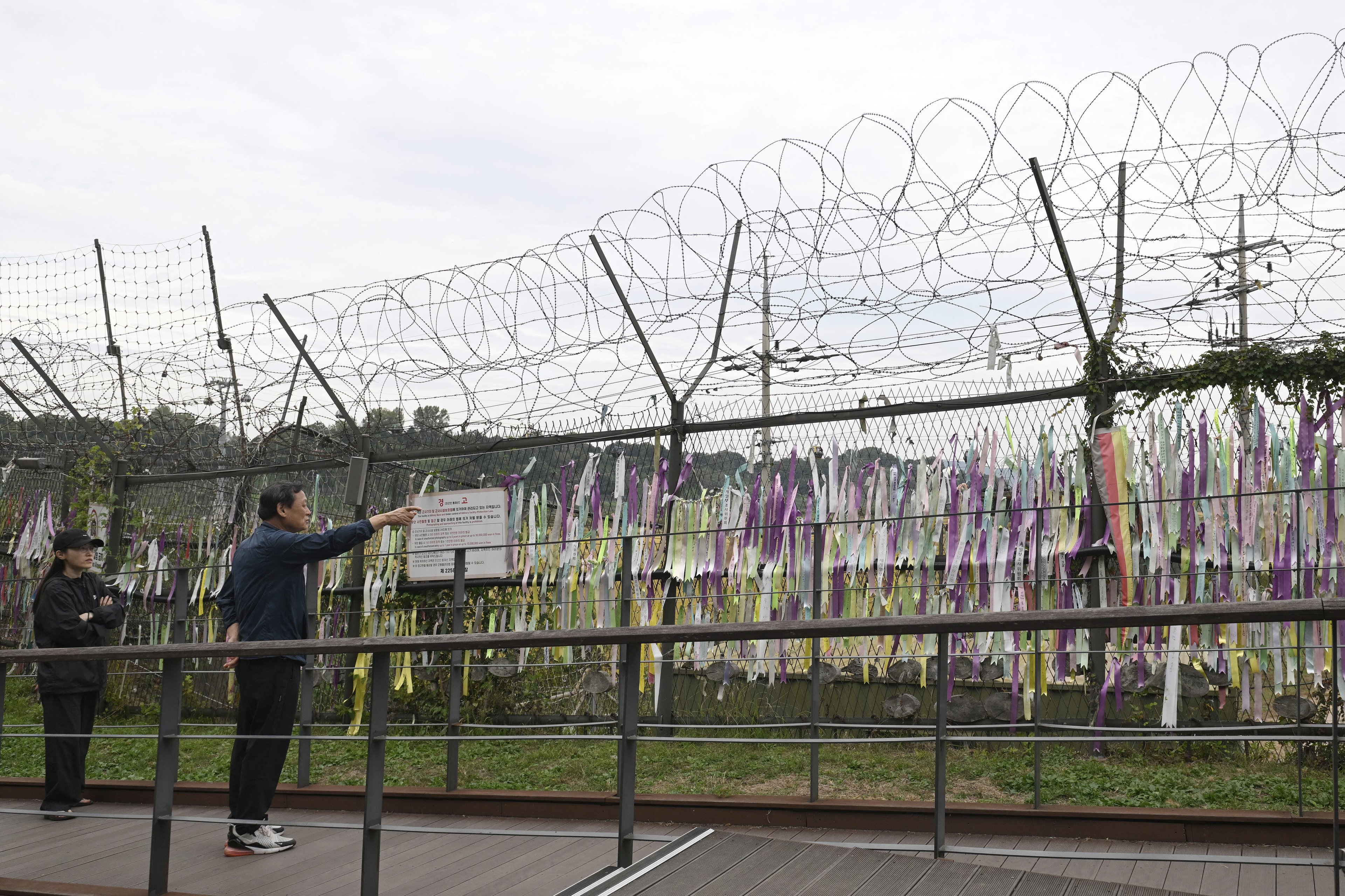 Visitantes passam por uma cerca militar no parque da paz Imjingak, perto da Zona Desmilitarizada (DMZ), que divide as duas Coreias em Paju, em 14 de outubro de 2024. Os militares da Coreia do Sul disseram em 14 de outubro que estavam 