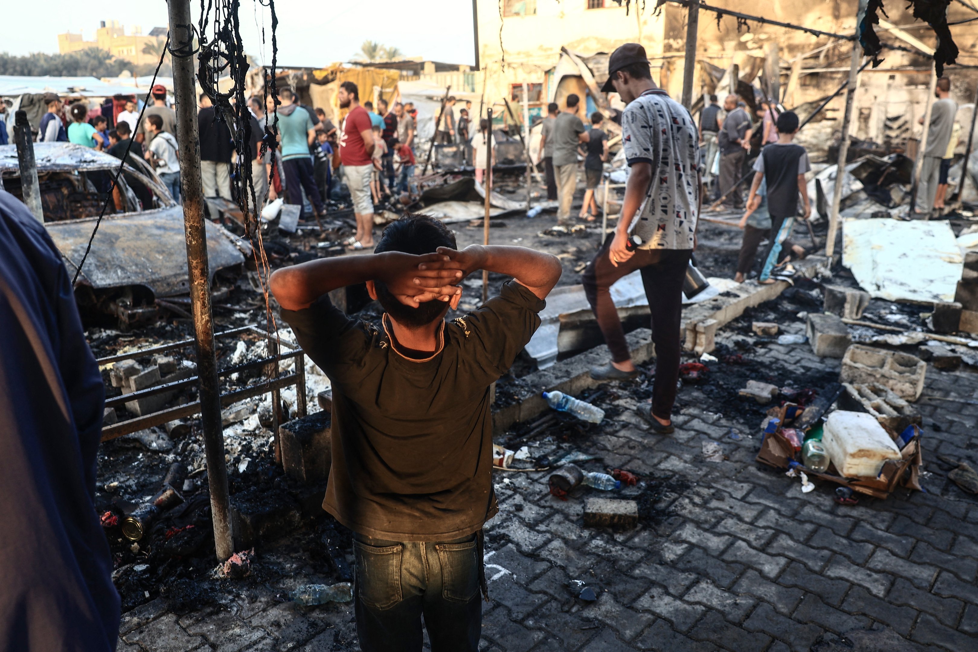 Um menino palestino gesticula enquanto as pessoas verificam a destruição após um ataque do exército israelense em torno de tendas para pessoas deslocadas dentro dos muros do Hospital dos Mártires de Al-Aqsa em Deir al-Balah, no centro da Faixa de Gaza, em 14 de outubro, 2024 em meio à guerra em curso entre Israel e o Hamas