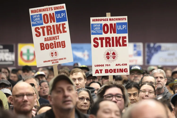 Pessoas seguram cartazes durante um comício de greve da Associação Internacional de Maquinistas e Trabalhadores Aeroespaciais (IAM) no Seattle Union Hall em Seattle, Washington, em 15 de outubro de 2024 (Jason Redmond/AFP)