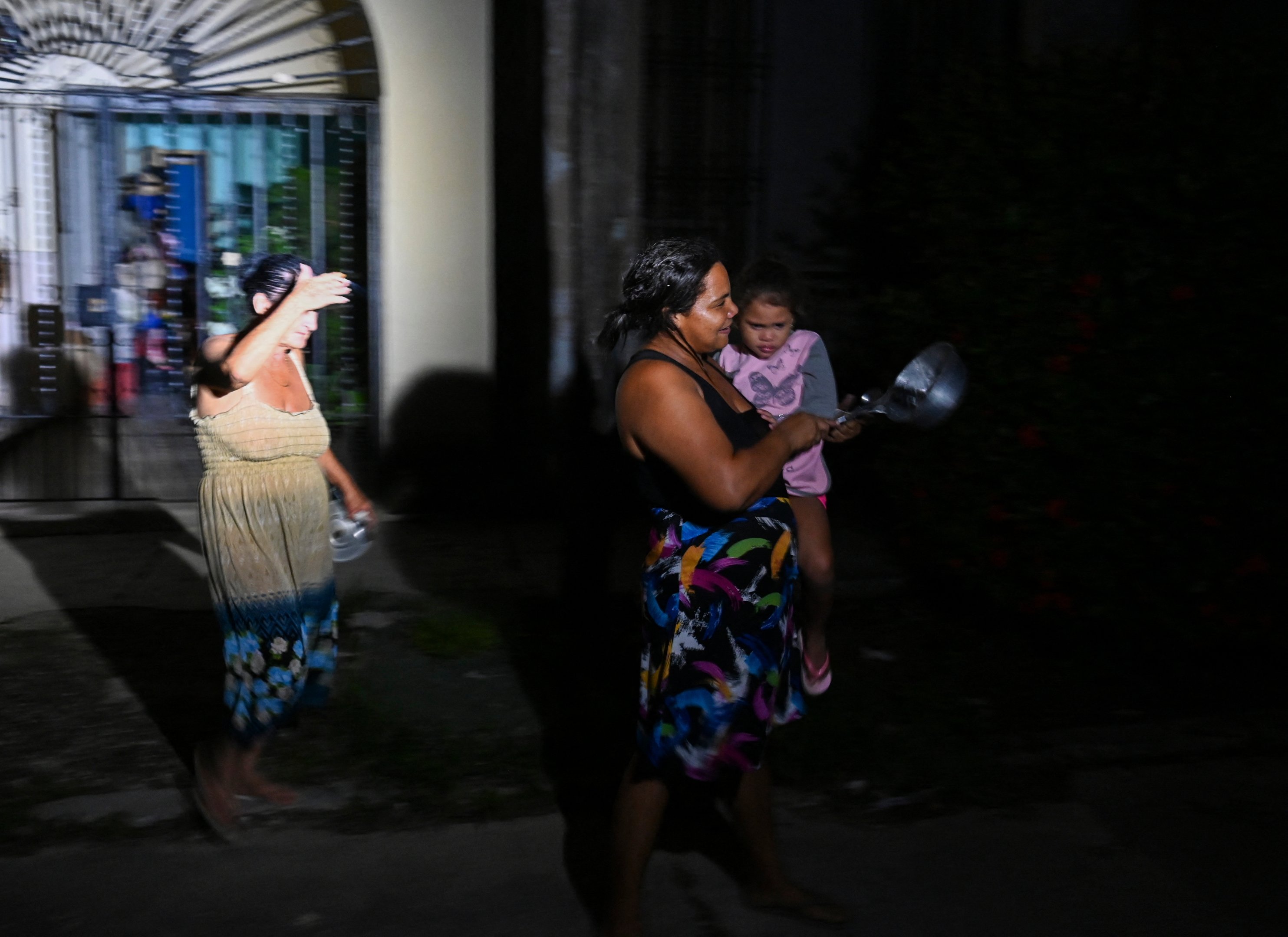 Cubanos usam panelas para exigir eletricidade durante a terceira noite de um apagão nacional em Havana, em 20 de outubro de 2024. O presidente cubano Miguel Díaz-Canel alertou no domingo que agirá com "rigor" contra aqueles que tentarem perturbar a ordem pública, em meio a um apagão total que manteve a ilha na escuridão por três noites