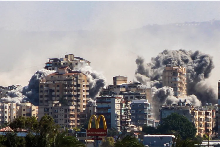 Uma foto tirada da cidade de Tiro, no sul do Líbano, mostra fumaça subindo do local de um ataque aéreo israelense que teve como alvo a vila de Al-Hawsh, nos arredores da cidade, em 22 de outubro de 2024 ( Kawnat HAJU/AFP)