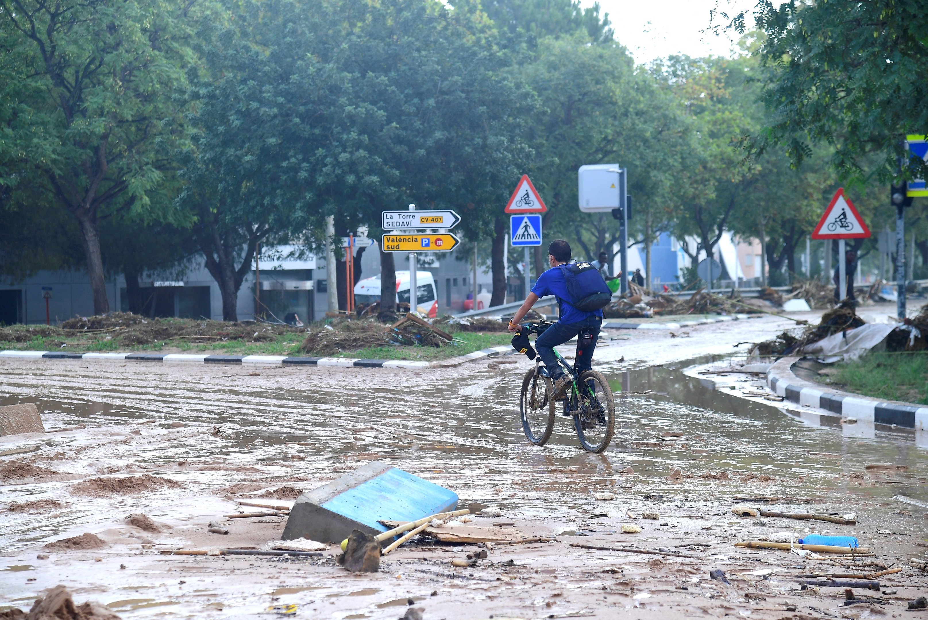 Um homem anda de bicicleta numa rua coberta de lama após as inundações em Picanya, perto de Valência, leste de Espanha, em 30 de outubro de 2024. As inundações provocadas por chuvas torrenciais na região de Valência, no leste de Espanha, deixaram 51 mortos, disseram os serviços de resgate em 30 de outubro