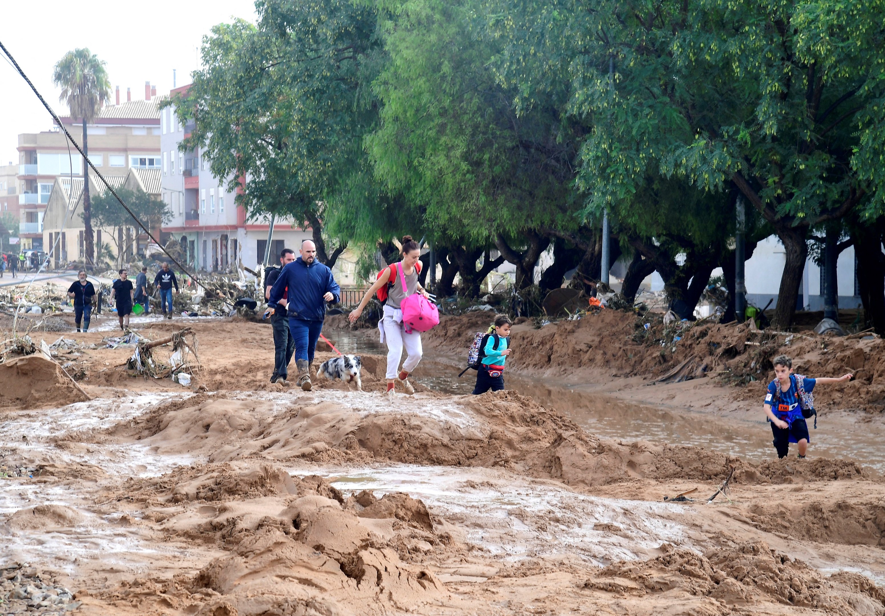 Familiares caminham em uma rua coberta de lama em uma área inundada em Picanya, perto de Valência, leste da Espanha, em 30 de outubro de 2024. Inundações provocadas por chuvas torrenciais na região de Valência, no leste da Espanha, deixaram 51 mortos, disseram serviços de resgate em 30 de outubro.