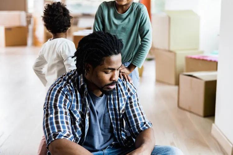 Young black father feeling sad after relocating into new home with his kids. (skynesher/Getty Images)