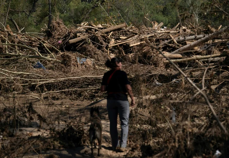 Cheryl Phillips e seu cão, Kite, buscam cadáveres após a passagem do furacão Helene por Burnsville, Carolina do Norte, em 5 de outubro de 2024 (AFP)