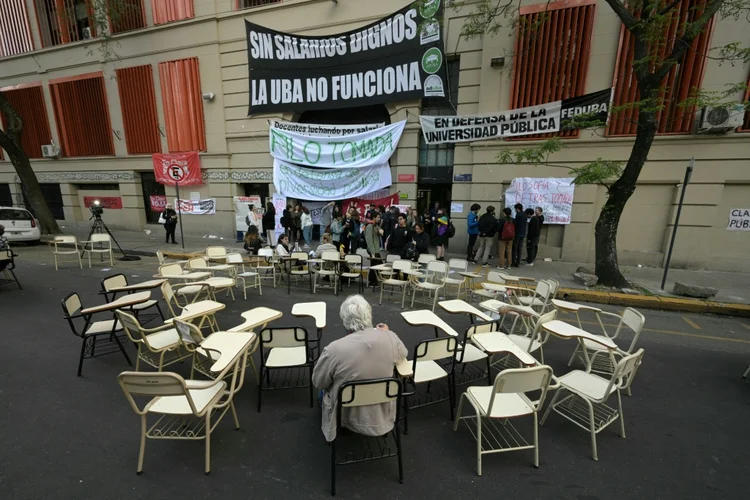 Um homem sentado em uma mesa em frente à Faculdade de Filosofia e Letras da Universidade de Buenos Aires (UBA) durante um protesto contra o veto do presidente da Argentina, Javier Milei, à uma lei recentemente aprovada pelo Congresso para melhorar o orçamento das instituições de Ensino Superior (AFP)