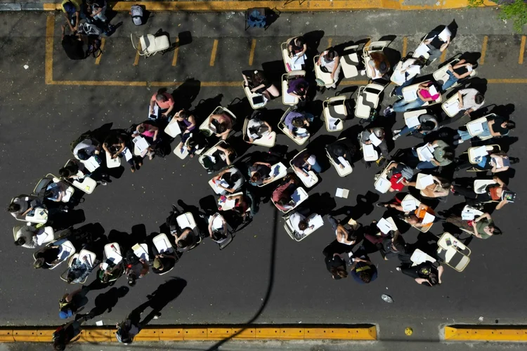 Estudantes assistem a uma aula no meio da rua em frente à Faculdade de Filosofia e Letras da Universidade de Buenos Aires, em 16 de outubro de 2024 (Agence France-Presse/AFP)