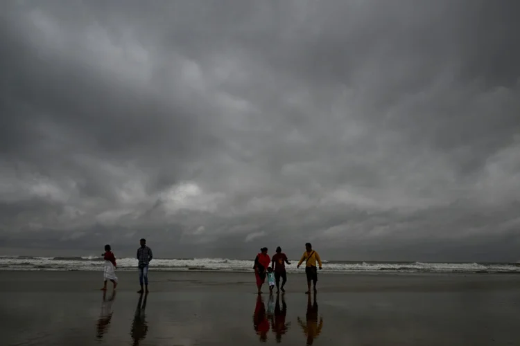 Pessoas caminham pela praia de Digha, na baía de Bengala, em 24 de outubro de 2024 (AFP)