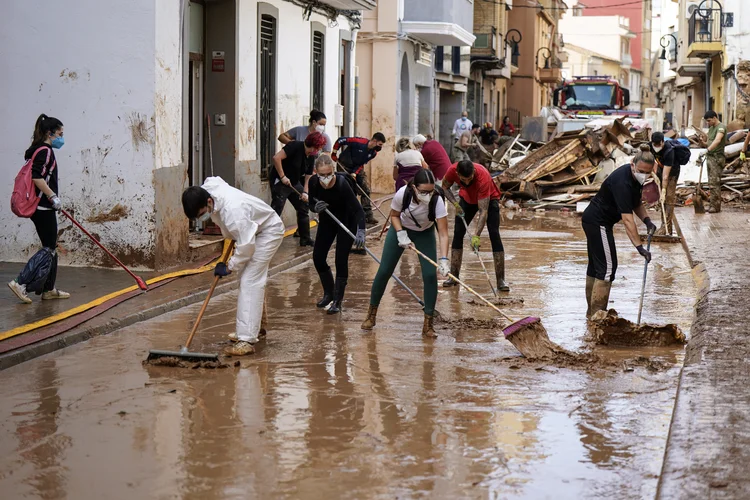 Pessoas trabalham para limpar lama e detritos de uma rua em Aldaia, na região de Valência, leste da Espanha, em 5 de novembro de 2024, após inundações devastadoras. O número de mortos nas piores inundações da Espanha em uma geração subiu para 219, de acordo com pesquisadores (CESAR MANSO/AFP)