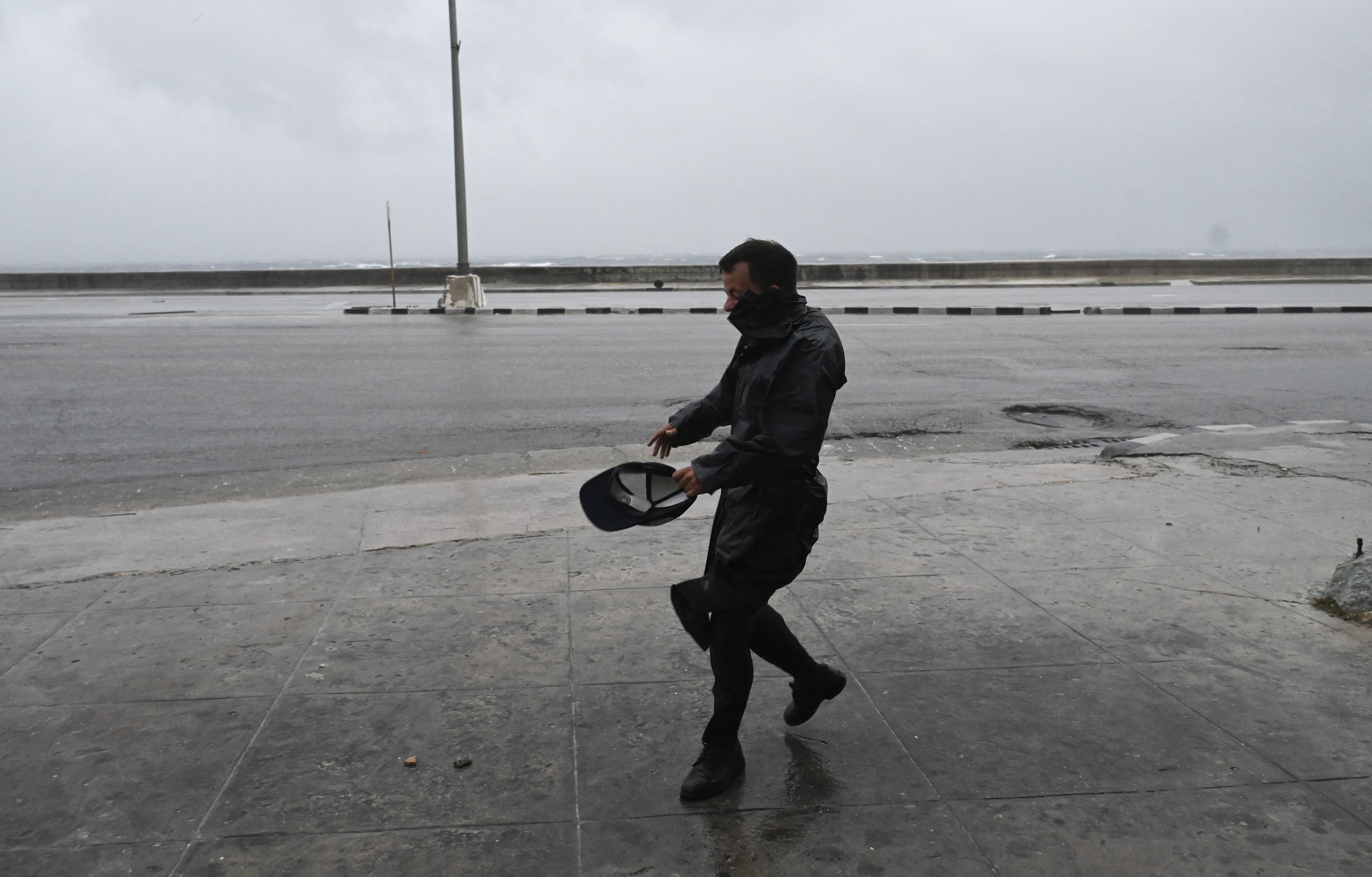 Um homem caminha sob ventos fortes após a chegada do furacão Rafael em Havana em 6 de novembro de 2024. O furacão Rafael cortou o fornecimento de energia para toda Cuba na quarta-feira ao atingir a ilha, que ainda se recupera de um apagão recente e de uma grande tempestade anterior, disse a empresa nacional de energia.