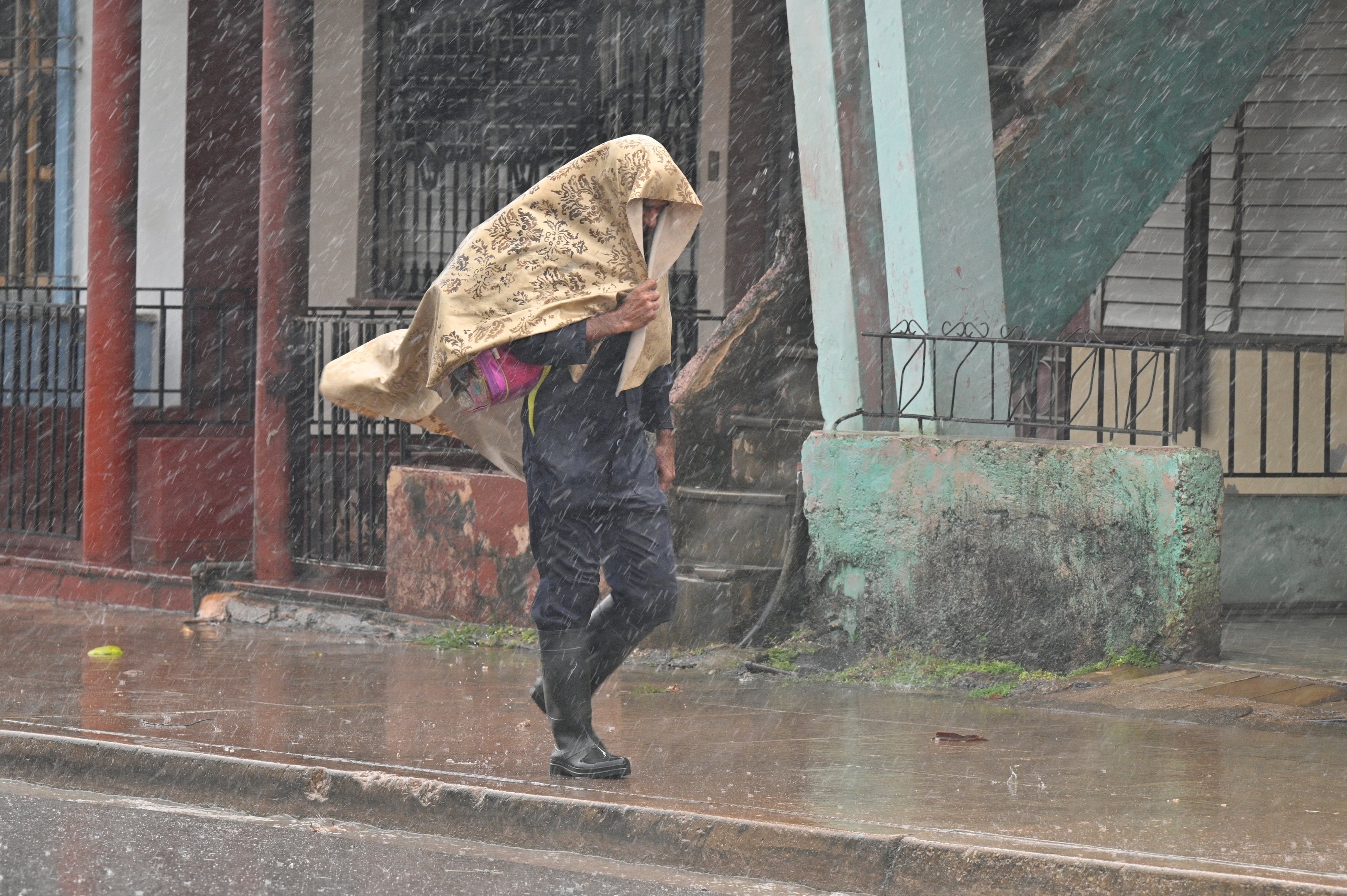 Um homem caminha na chuva após a chegada do furacão Rafael em Pueblo Candelaria, província de Artemisa, 65 km a oeste de Havana, em 6 de novembro de 2024. O furacão Rafael cortou a energia de toda Cuba na quarta-feira ao atingir a ilha, que ainda se recupera de um apagão recente e de uma grande tempestade anterior, disse a empresa nacional de energia