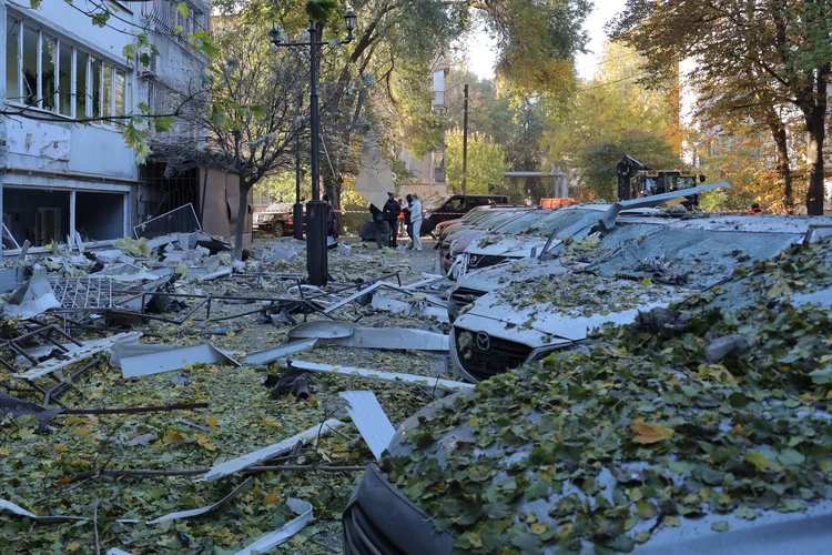 Moradores locais ficam ao lado de carros danificados no pátio de um prédio residencial após um ataque de drones em Odessa em 7 de novembro de 2024 (Oleksandr GIMANOV/AFP)