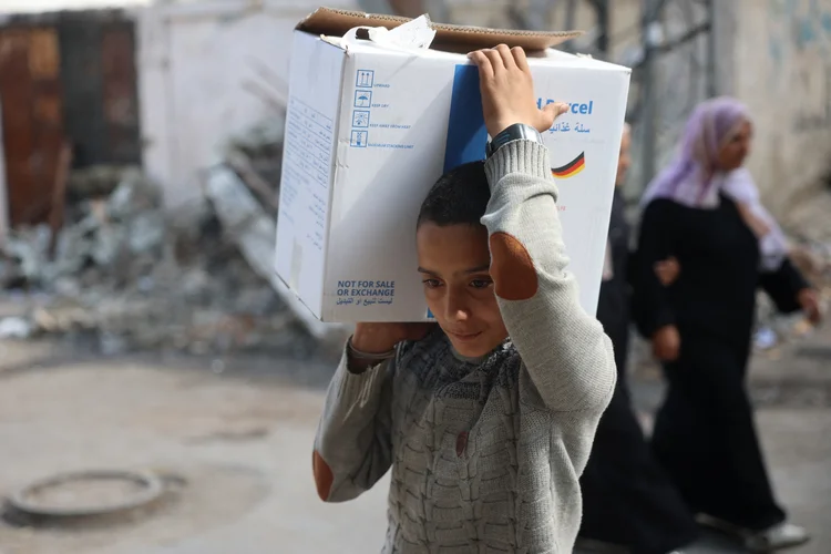 Um menino transporta uma caixa de ajuda humanitária, fornecida pelo Programa Mundial de Alimentos, de volta para sua casa no campo de refugiados de Bureij (Eyad BABA/AFP)