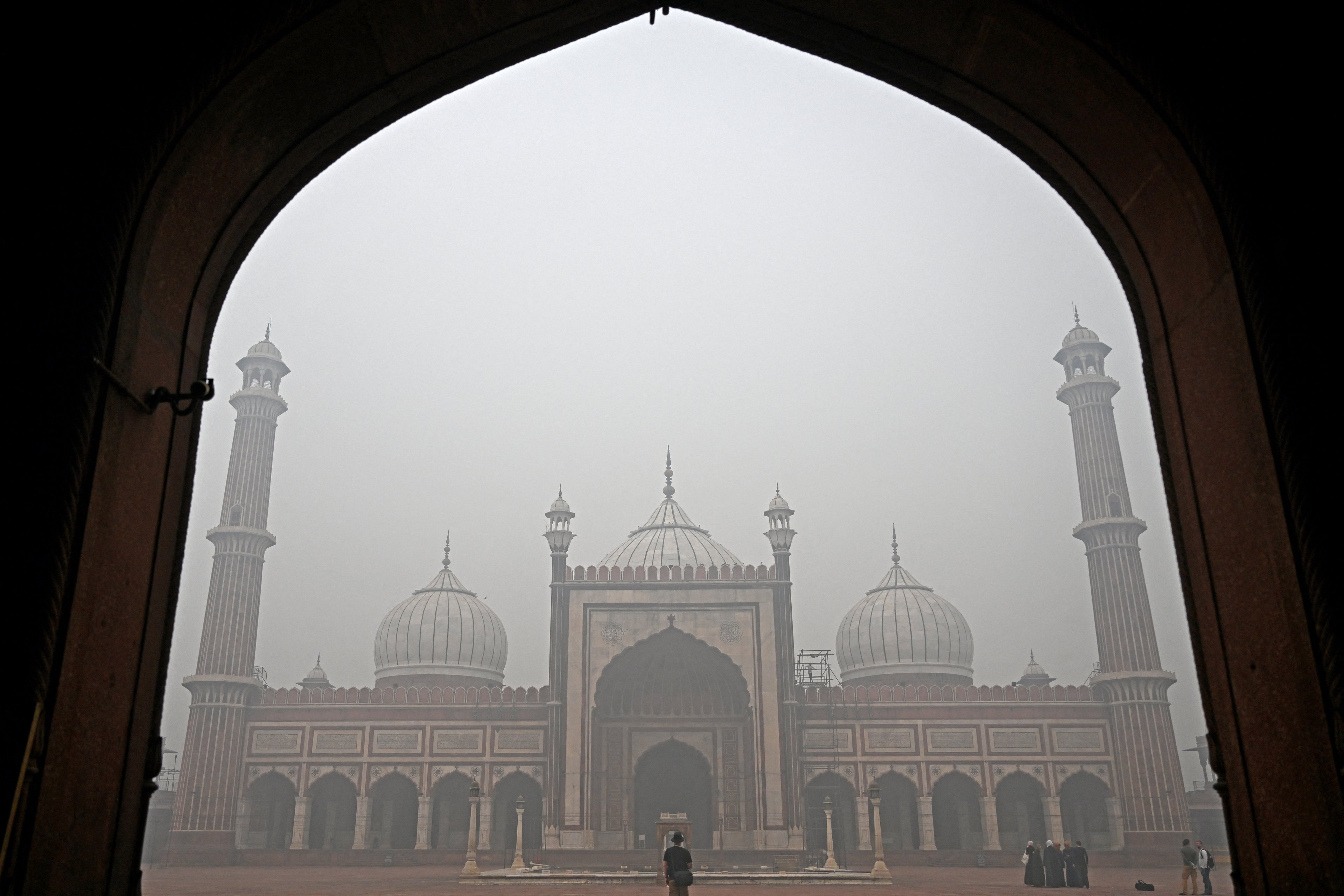 Turistas visitam Jama Masjid em meio a uma espessa poluição atmosférica, nos bairros antigos de Déli, em 18 de novembro de 2024. Moradores da capital da Índia, Nova Déli, sufocaram em uma névoa tóxica em 18 de novembro, enquanto a poluição do ar piorava e ultrapassava 60 vezes o máximo diário recomendado pela Organização Mundial da Saúde