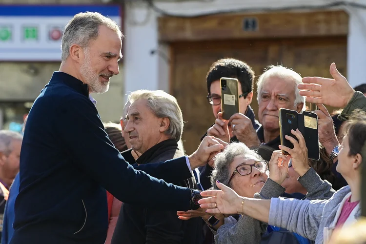 O rei Felipe VI da Espanha cumprimenta os moradores durante uma visita à cidade de Chiva, danificada pelas enchentes, na região de Valência, leste da Espanha, após inundações catastróficas e mortais, em 19 de novembro de 2024. O rei Felipe VI da Espanha e a rainha Letizia estão retornando para visitar a área depois de terem sido vaiados por moradores furiosos durante sua primeira visita à região de Valência, onde inundações catastróficas em outubro deixaram pelo menos 226 mortos, de acordo com autoridades (JOSE JORDAN/AFP)