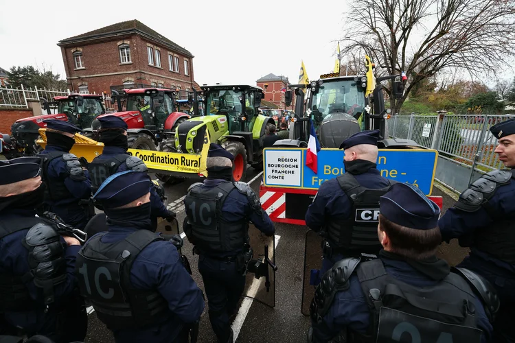 Oficiais do Corpo de Segurança Republicano (CRS) da polícia nacional francesa ficam em frente a tratores enquanto fazendeiros franceses participam de uma manifestação organizada pela Coordination Rurale, um sindicato de fazendeiros francês, para protestar contra o acordo UE-Mercosul (Frederick FLORIN/AFP)