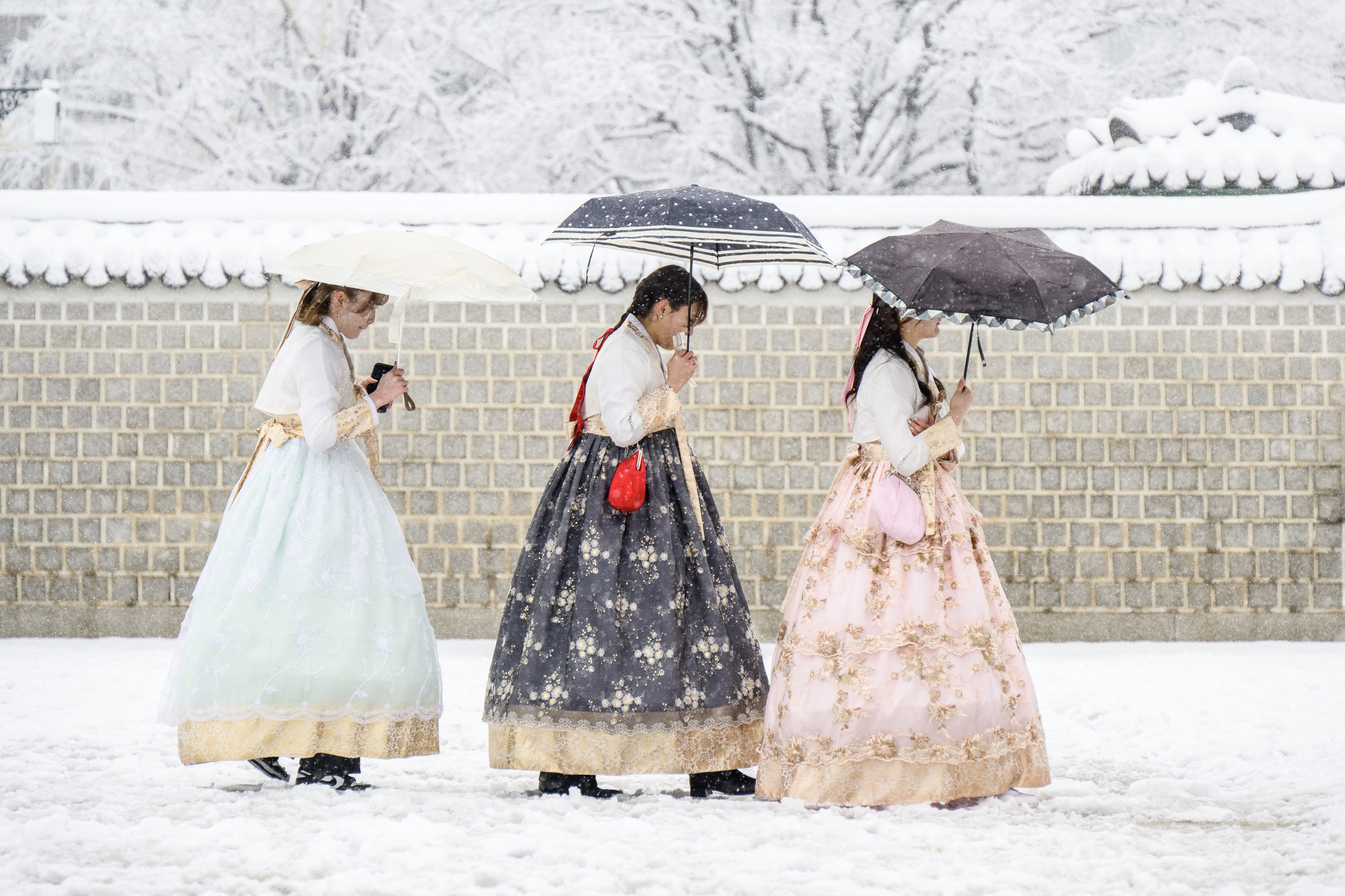 Visitantes usando vestidos tradicionais hanbok são vistos no terreno do Palácio Gyeongbokgung em meio a uma forte nevasca no centro de Seul em 27 de novembro de 2024. A capital da Coreia do Sul foi coberta em 27 de novembro pela maior nevasca de novembro desde que os registros começaram há mais de um século, disse a agência meteorológica